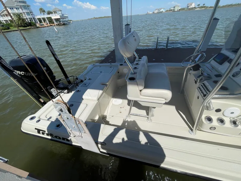 Slide: The Image of 2014 Triton 240 LTS Pro boat docked by a scenic waterfront. - 8