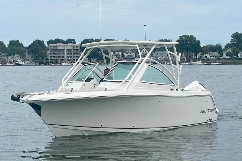 Slide: The Image of 2025 Sailfish 245 DC boat on calm water, with coastal background. - 2