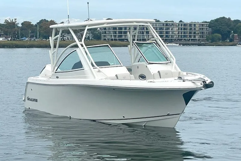 Slide: The Image of 2025 Sailfish 245 DC boat on calm water near shoreline buildings. - 5