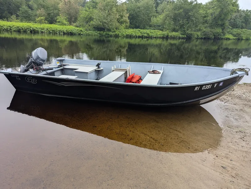 Slide: The Image of 2010 G3 Guide V16 boat on a calm riverbank with lush greenery. - 2