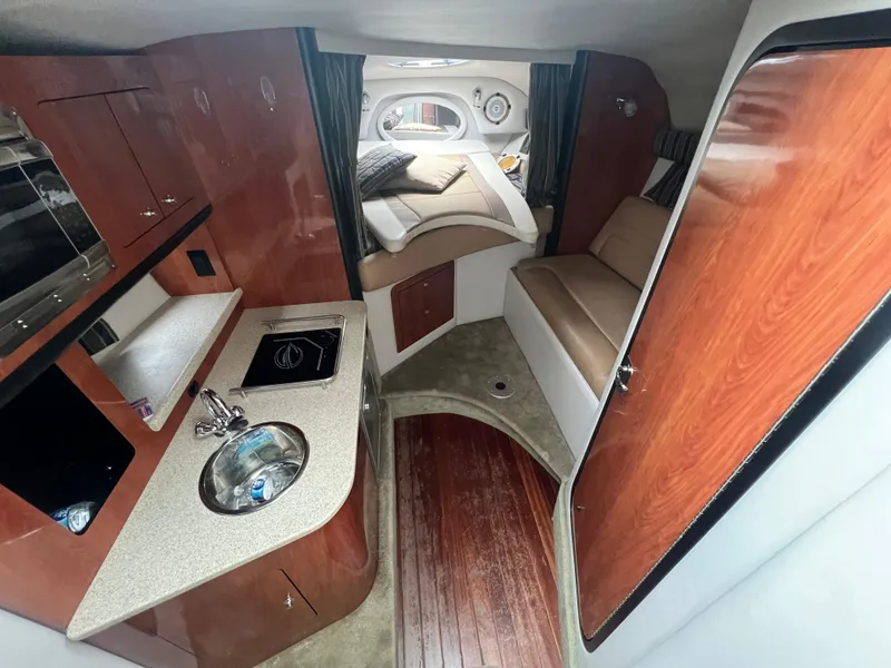 Slide: The Image of 2014 Crownline 294 CR cabin interior with kitchenette, seating, and bed. - 17