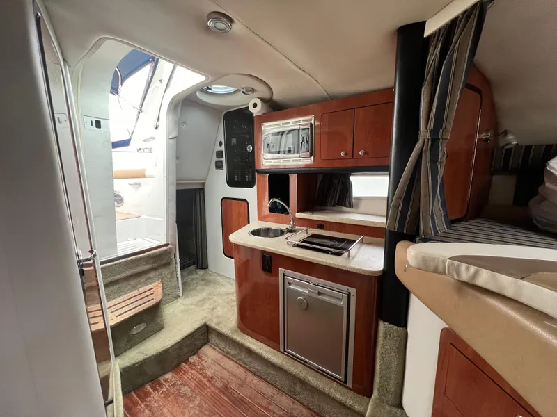Slide: The Image of 2014 Crownline 294 CR cabin interior with kitchenette and seating area. - 18