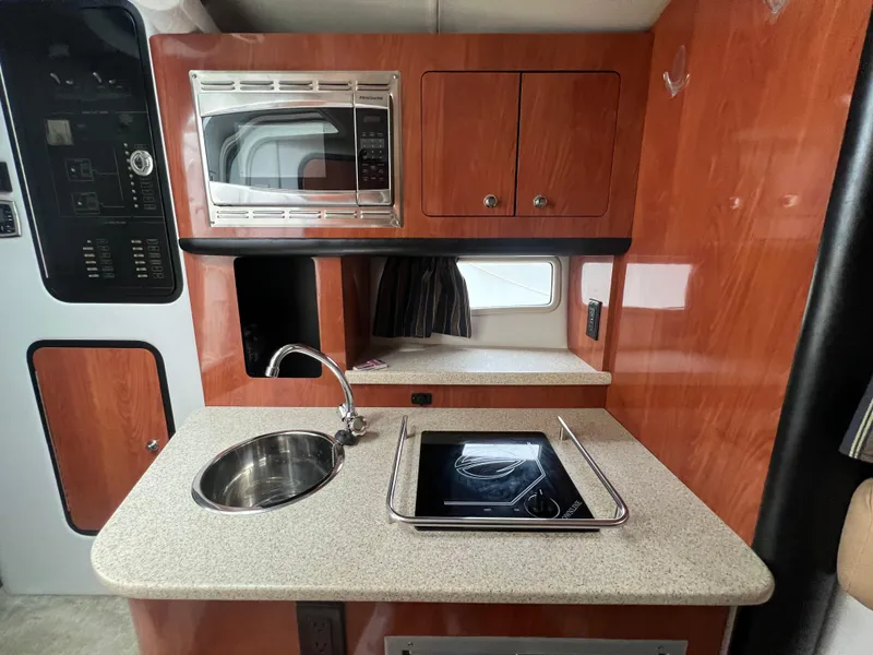 Slide: The Image of 2014 Crownline 294 CR boat kitchen with sink, stove, and microwave. - 19