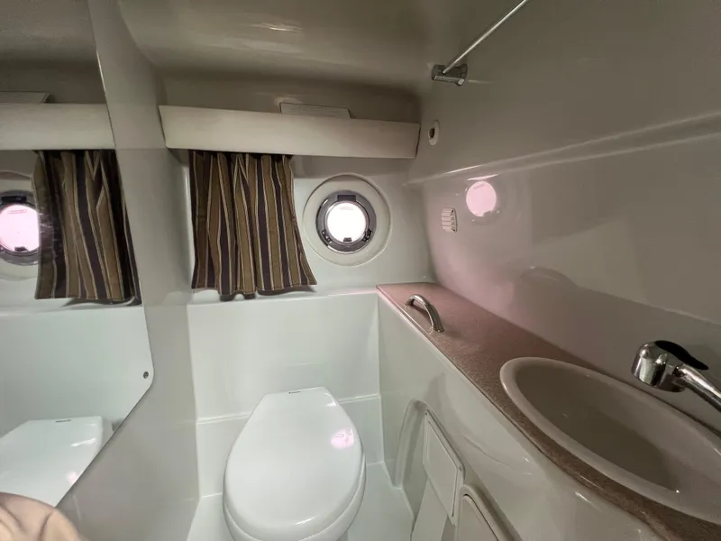 Slide: The Image of 2014 Crownline 294 CR boat bathroom with toilet, sink, and porthole window. - 28