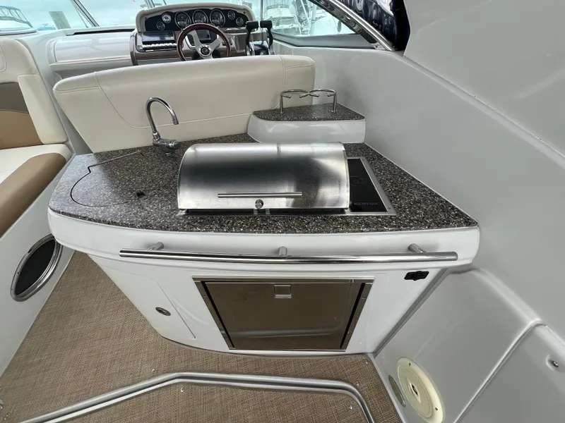 Slide: The Image of 2014 Crownline 294 CR boat interior with kitchenette and steering area. - 6