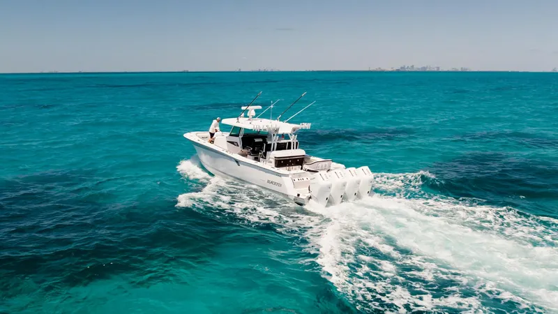 Slide: The Image of 2024 Blackfin 400CC boat cruising on clear turquoise ocean waters. - 10