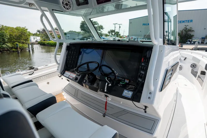 Slide: The Image of 2024 Blackfin 400CC boat cockpit with modern controls and seating, docked near a marina. - 18