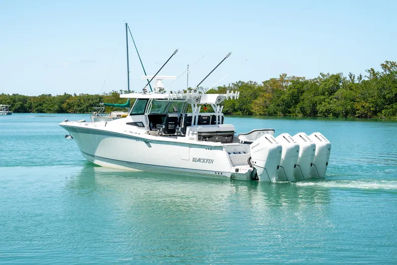 Slide: The Image of 2024 Blackfin 400CC boat cruising on calm water with lush greenery in the background. - 6