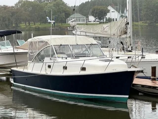 The Image of 2002 Mainship Pilot 34 boat docked in a serene marina setting. - 0