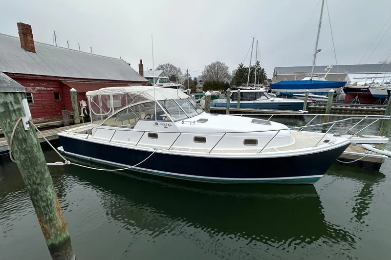 Slide: The Image of 2002 Mainship Pilot 34 docked at a marina, featuring a sleek design and enclosed cockpit. - 15