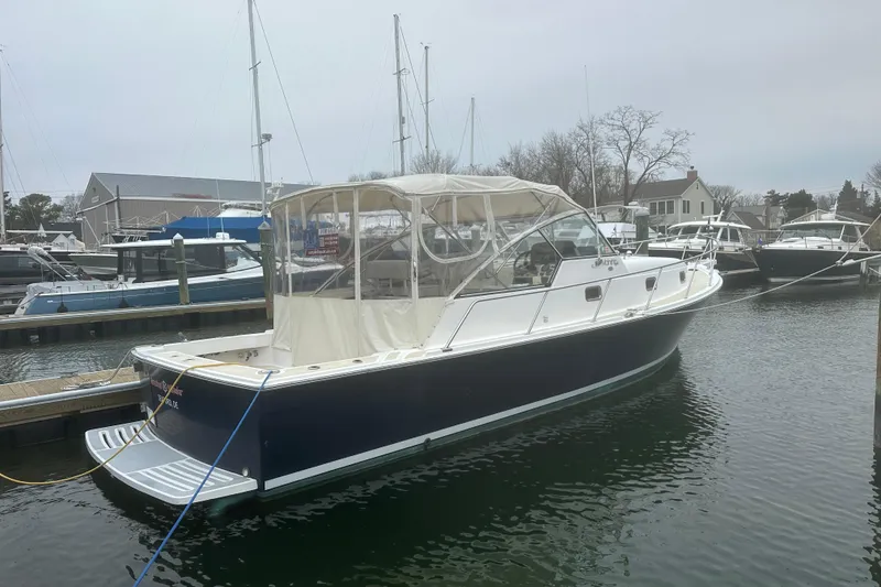 Slide: The Image of 2002 Mainship Pilot 34 docked at marina, featuring a blue hull and white canopy. - 16