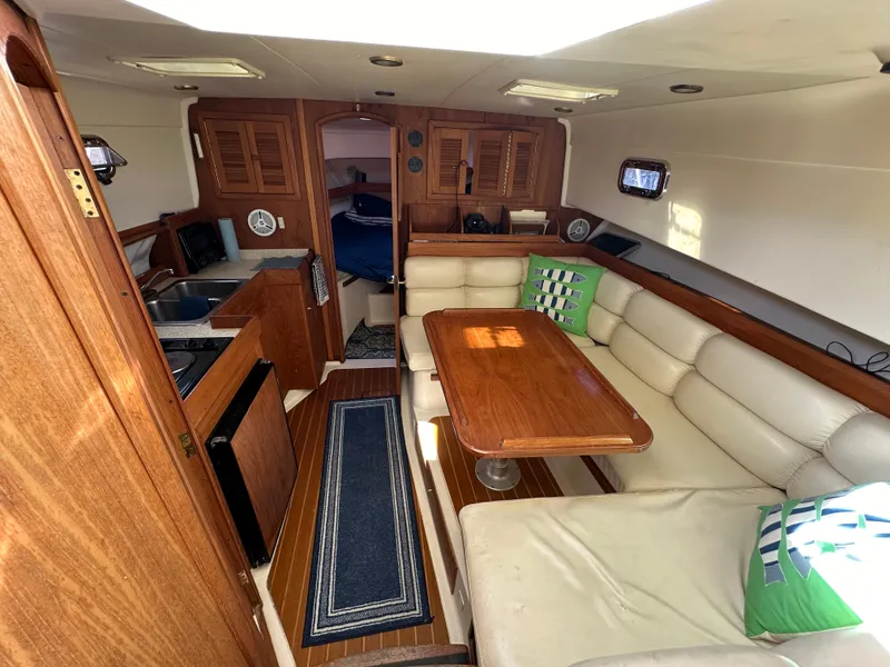 Slide: The Image of 2002 Mainship Pilot 34 interior with wood finish, dining area, and kitchenette. - 8
