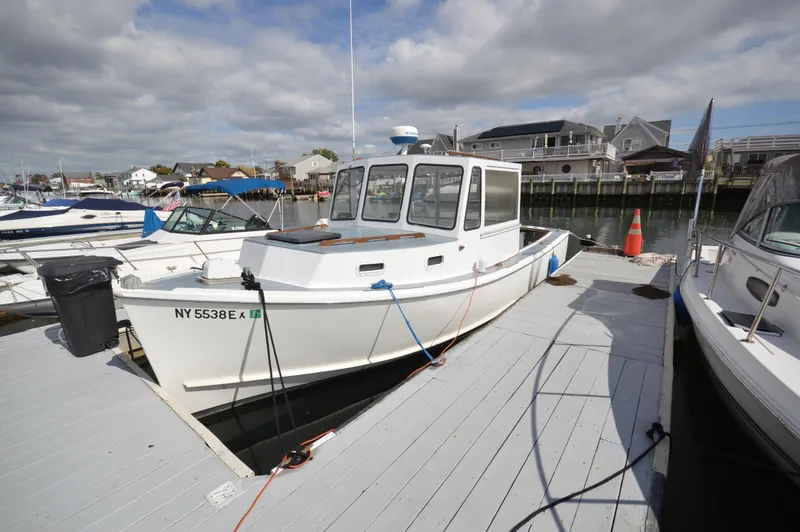 The Image of 1983 BHM 25 EXPRESS boat docked at a marina under cloudy skies. - 1