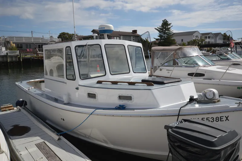 Slide: The Image of 1983 BHM 25 EXPRESS boat docked in a marina under a partly cloudy sky. - 14