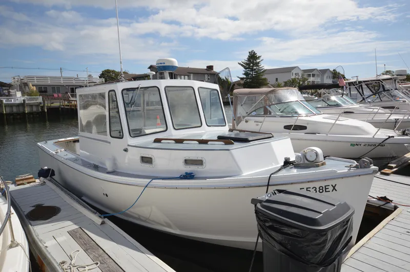 Slide: The Image of 1983 BHM 25 EXPRESS boat docked at marina, surrounded by other vessels. - 15