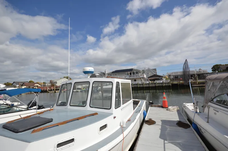 Slide: The Image of 1983 BHM 25 EXPRESS boat docked at marina under cloudy sky. - 2