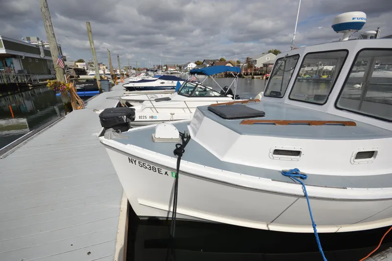 Slide: The Image of 1983 BHM 25 EXPRESS boat docked at marina with other vessels under cloudy sky. - 3