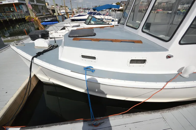 Slide: The Image of 1983 BHM 25 EXPRESS boat docked at marina, featuring white and gray exterior. - 4