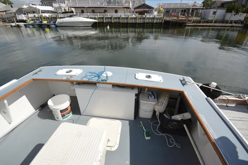 Slide: The Image of 1983 BHM 25 EXPRESS boat deck with fishing gear, docked by calm waters. - 6