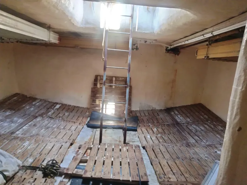 Slide: The Image of Interior of a 1972 commercial shrimp freezer trawler with wooden pallets and ladder. - 13