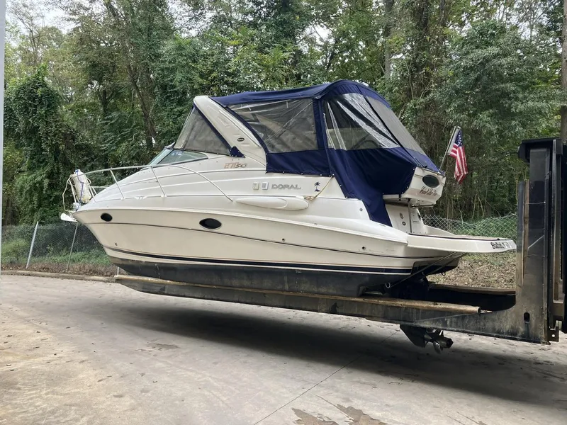 Slide: The Image of 2001 Doral 270 SC boat on trailer, covered, surrounded by trees. - 3