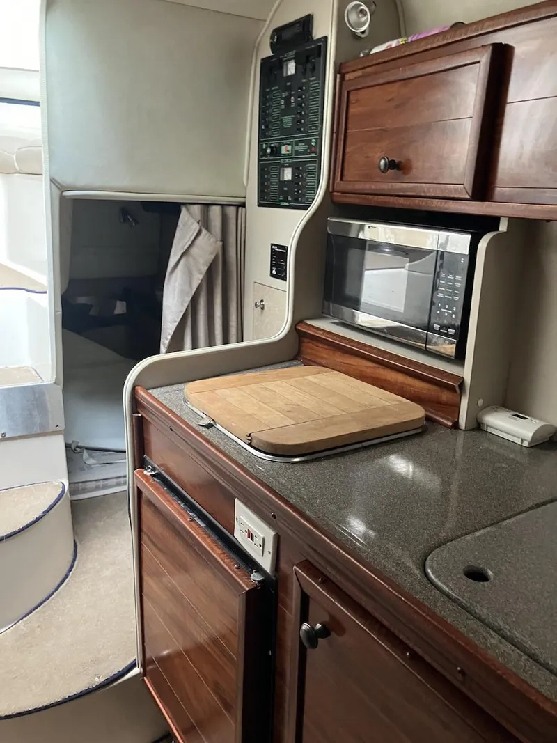 Slide: The Image of 2001 Doral 270 SC boat interior with kitchenette, microwave, and wooden cabinets. - 8