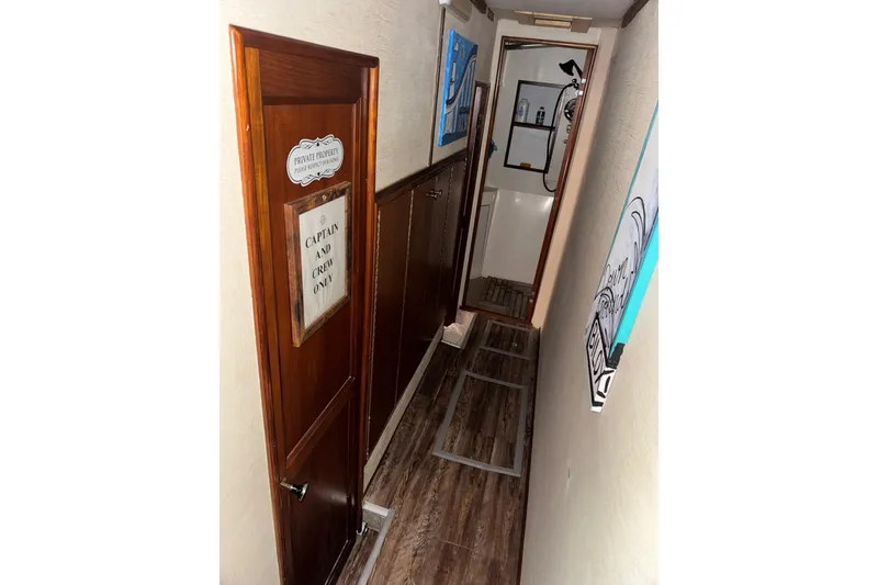 Slide: The Image of Narrow hallway inside 1987 Ocean Yachts 63 convertible Manns, featuring wooden door and nautical decor. - 16