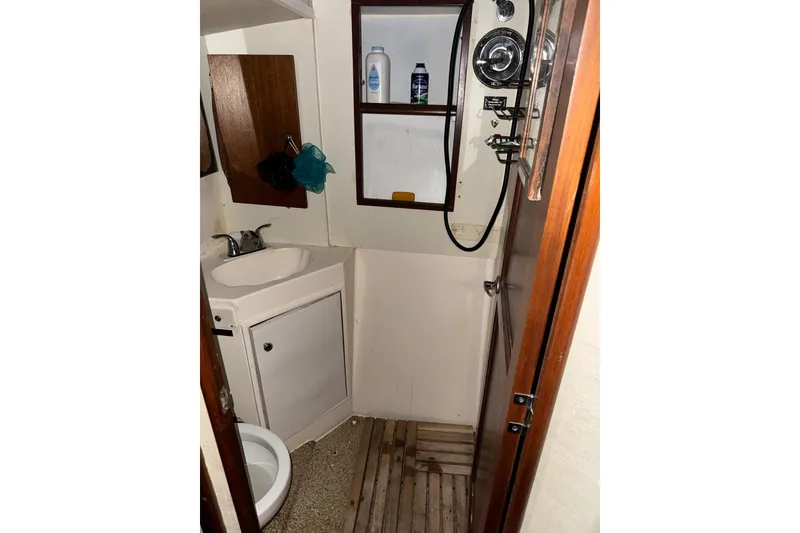 Slide: The Image of 1987 Ocean Yachts 63 Convertible Manns bathroom with sink, shower, and wooden accents. - 17