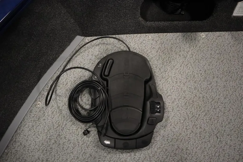 Slide: The Image of Foot pedal on Lowe 1775 FM WT boat, 2025 model, with coiled cable on carpeted floor. - 13