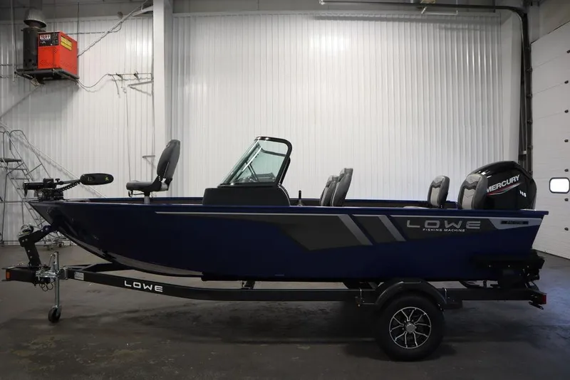 Slide: The Image of 2025 Lowe 1775 FM WT fishing boat in a garage, featuring a Mercury outboard motor. - 7