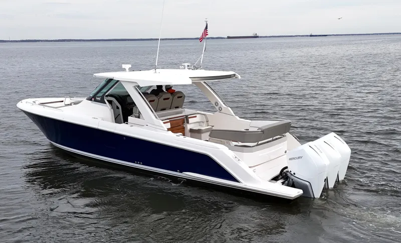 Slide: The Image of 2023 Tiara Yachts 38 LS boat on calm water, featuring sleek design and triple outboard engines. - 4