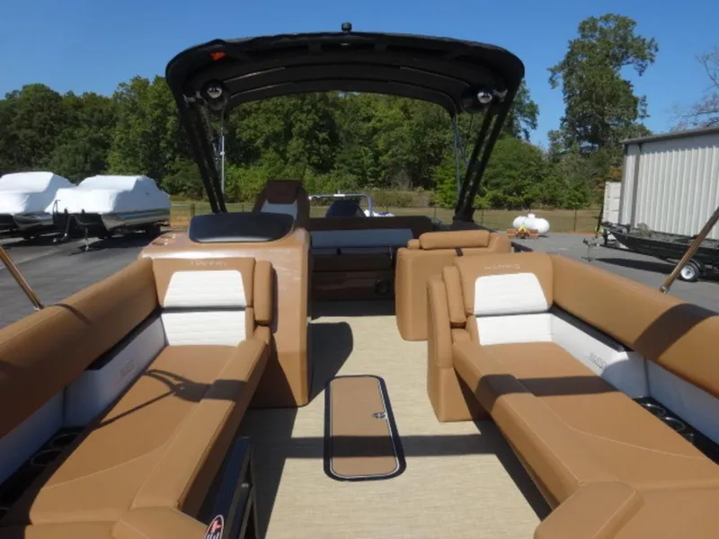 Slide: The Image of 2025 Harris Solstice 250 pontoon boat with tan seating and canopy, parked outdoors. - 3