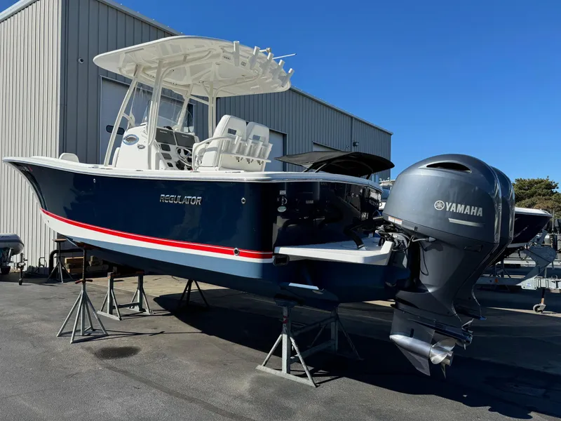 Slide: The Image of 2017 Regulator 25 CC boat with Yamaha engine, displayed outdoors on stands. - 2