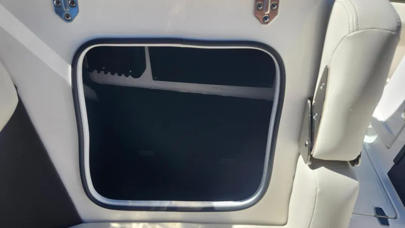 Slide: The Image of 2025 Regal LX6 boat storage compartment with open hatch and cushioned seating. - 18