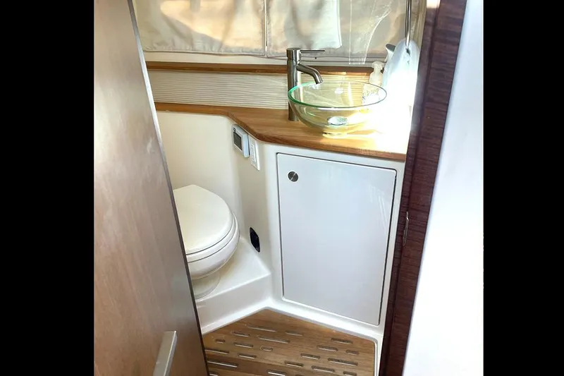 Slide: The Image of 2019 Sea Ray 350 Sundancer bathroom with modern sink and wooden accents. - 11