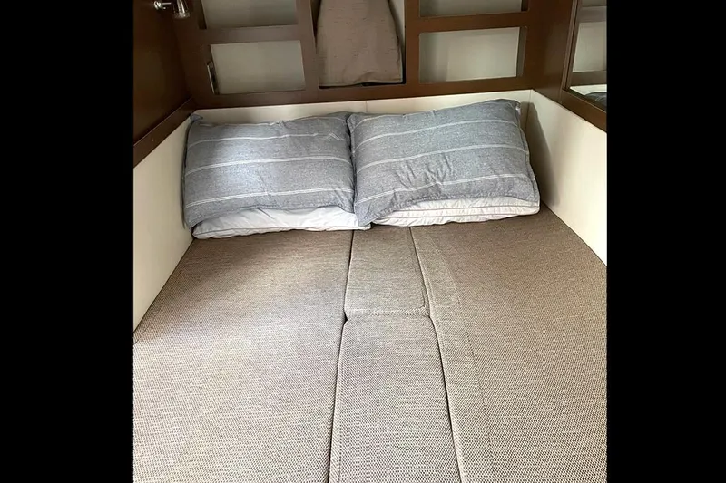 Slide: The Image of 2019 Sea Ray 350 Sundancer cabin bed with striped pillows. - 17