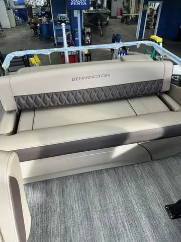 Slide: The Image of 2025 Bennington 25 QSBA boat interior with beige seating in a workshop. - 7