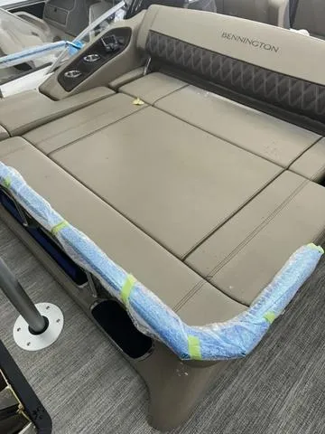 Slide: The Image of 2025 Bennington 25 QSBA boat interior with cushioned seating and protective wrapping. - 8