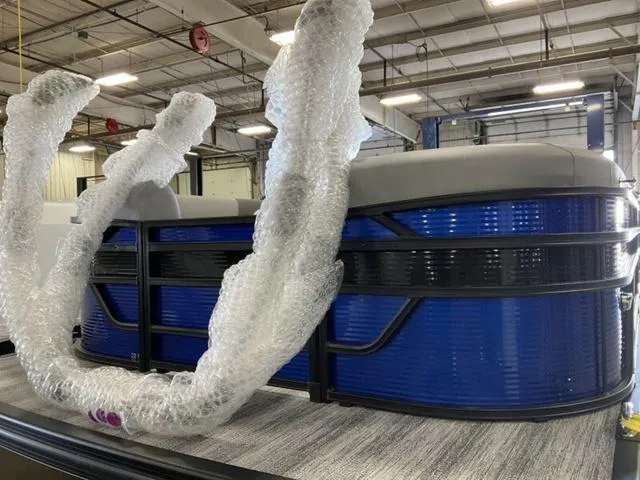 Slide: The Image of 2025 Bennington 22SSB-SPS pontoon boat in a warehouse, partially wrapped in bubble wrap. - 27