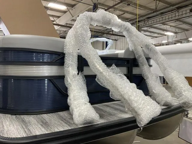 Slide: The Image of 2025 Bennington 22 SSR pontoon boat in a warehouse, partially wrapped in bubble wrap. - 21