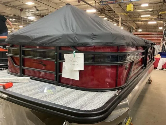 Slide: The Image of 2025 Bennington 23 SSB pontoon boat in a warehouse, covered with a black tarp. - 2