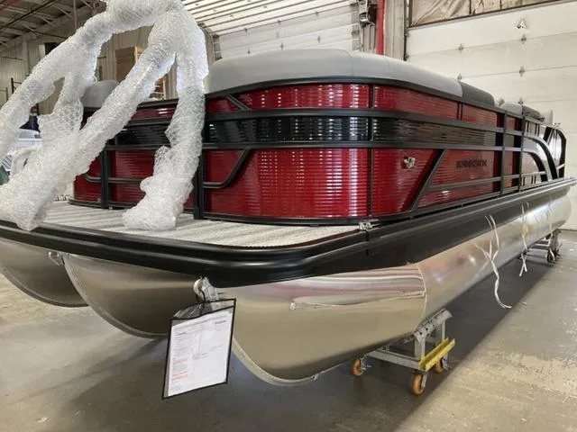 Slide: The Image of 2025 Bennington 23 SSB pontoon boat in a warehouse, featuring a sleek red and black design. - 7