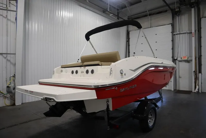 Slide: The Image of 2024 Bayliner DX2050 boat in a garage, red and white design, on a trailer. - 10