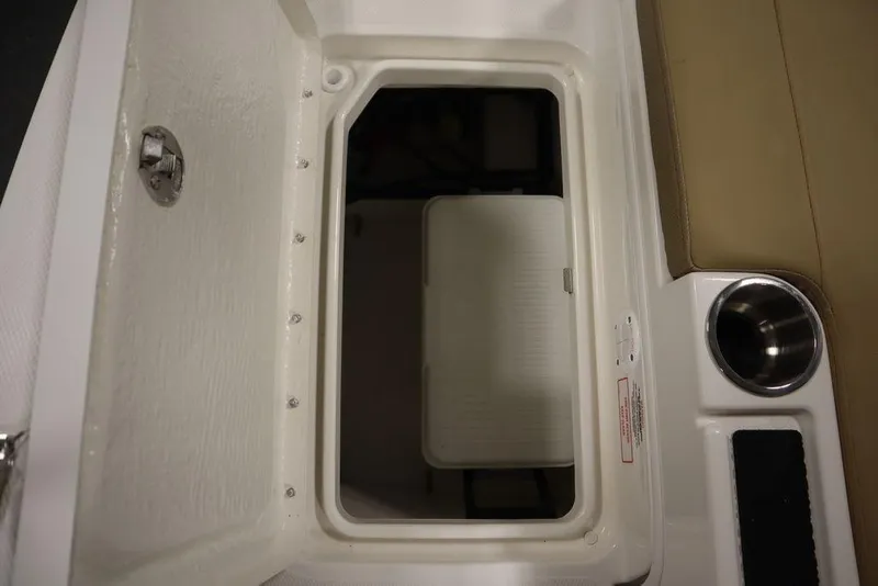 Slide: The Image of 2024 Bayliner DX2050 storage compartment with cup holder and beige seating. - 39