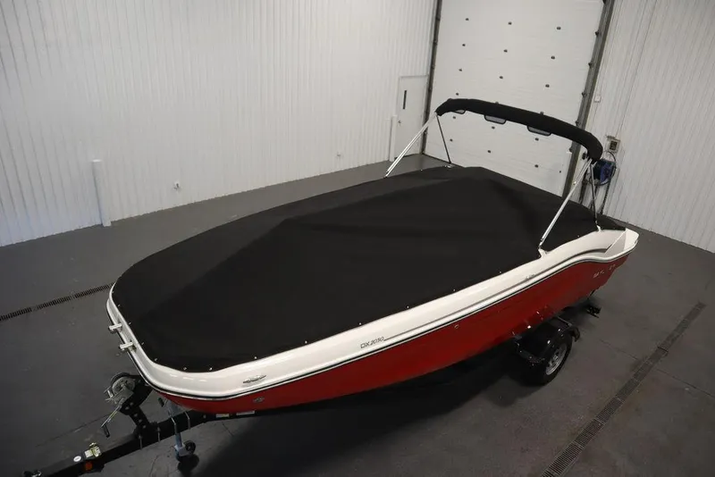 Slide: The Image of 2024 Bayliner DX2050 boat with black cover in a garage setting. - 44