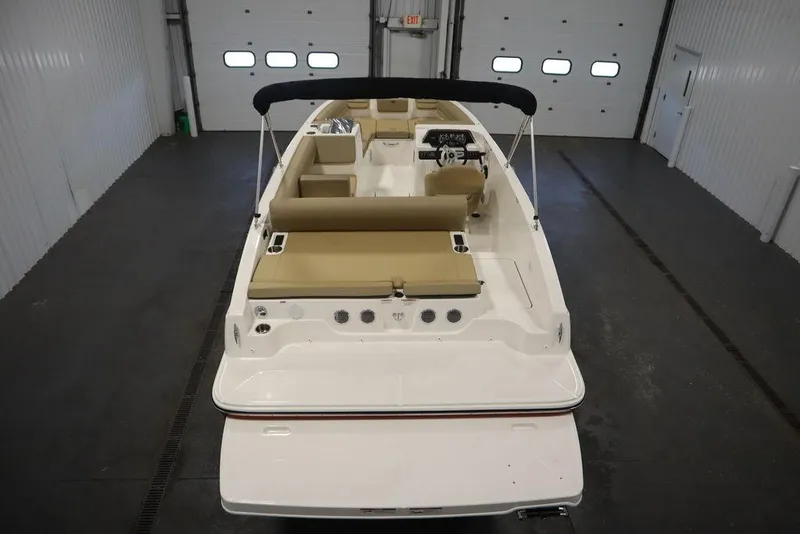 Slide: The Image of 2024 Bayliner DX2050 boat in indoor storage, rear view, beige seating, black canopy. - 8