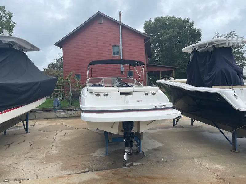 Slide: The Image of 2011 Bayliner 235 Bowrider boat on trailer, parked between covered boats. - 1