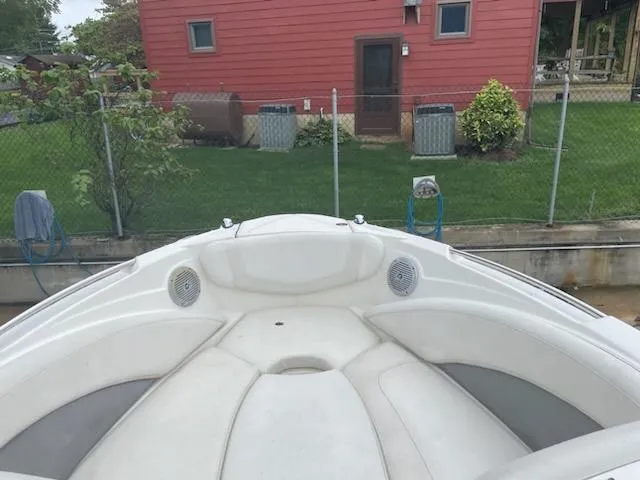 Slide: The Image of 2011 Bayliner 235 Bowrider boat with white seating, docked near a red house. - 15