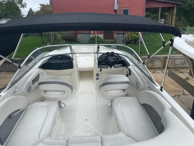 Slide: The Image of 2011 Bayliner 235 Bowrider with white interior and black canopy, docked outdoors. - 20