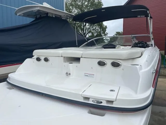 Slide: The Image of 2011 Bayliner 235 Bowrider boat with black canopy, docked outdoors. - 21
